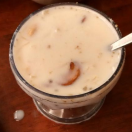 A table with a glass of yummy,sweet milk and a spoon displays a dairy Product,pudding.