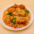 A delicious dinner of yummy fried chicken, gravy, and rice is offered on a traditional wooden table.