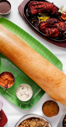 A lengthy Dosa accompanied by sauces on a green plate is a tasty Indian dish that is presented