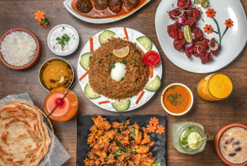 A table is laden with dishes from Indian cuisine, including curry, naan, samosas, and rice.