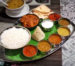 Plate that offers a tasty, featuring a delicious blend of rice, curries, & several vegetable dishes