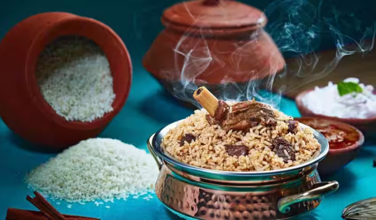 A delicious flavored chicken biryani served in a copper pot along with a leg piece, gravy & raitha.