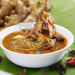 Aromatic South Indian chicken gravy with meat is served on a banana leaf, showing the ingredients.
