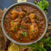A flavorful and rich dish, chicken curry in a bowl, is decorated with a slice of lemon and coriander