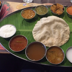 A bowl filled with a variety of vegetarian foods such as applam dal, rasam for a tasty Indian recipe