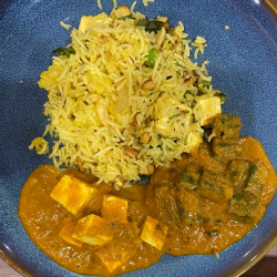 A plate of biriyani with paneer curry, tofu, and vegetables makes a colorful and delicious food