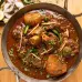 A substantial bowl of stew that has been well cooked, featuring soft meat and vibrant veggies