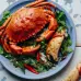 A large serving of flavorful grilled crab that has been enriched with sauce and seasoned with leaves