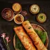 A platter is presented with two slices of the classic Indian dosa with traditional Indian chutneys