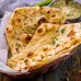 Two pieces of the traditional Indian flatbread known as naan are present in the serving bowl