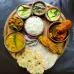 A dish filled with an array of delectable foods, such as cereals, meat, veggies, and thali